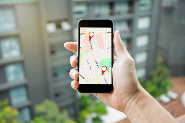 Hombre de la mano teléfono inteligente con GPS Mapa a la conexión de red Ruta Destino. Ubicación Mapa de calle con iconos GPS Navegación e icono rojo de la ubicación. Concepto de navegación en línea. - Foto, Imagen