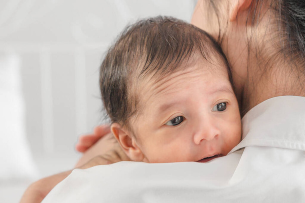 close up portrait of little infant baby holding over shoulder of mother - Fotoğraf, Görsel