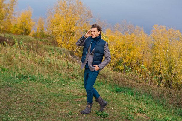 Tall handsome man walking outdoor in yellow autumn forest on the hill before storm - Valokuva, kuva
