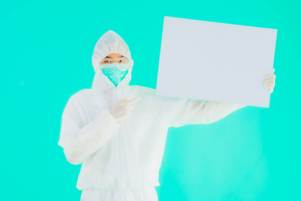 Портрет красива молода азіатська жінка-лікар носить рп або особисте захисне обладнання для захисту від коронавірусу або ковірусу19 з порожньою картковою білою дошкою на синьому ізольованому фоні
 - Фото, зображення