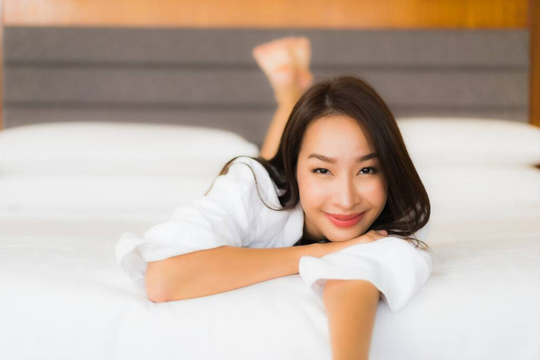 Retrato hermosa joven asiática mujer relajarse sonrisa en la cama en el interior del dormitorio - Foto, Imagen