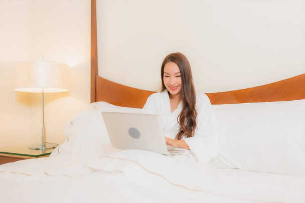 Porträt schöne junge asiatische Frau verwenden Laptop auf Bett im Schlafzimmer Interieur - Foto, Bild