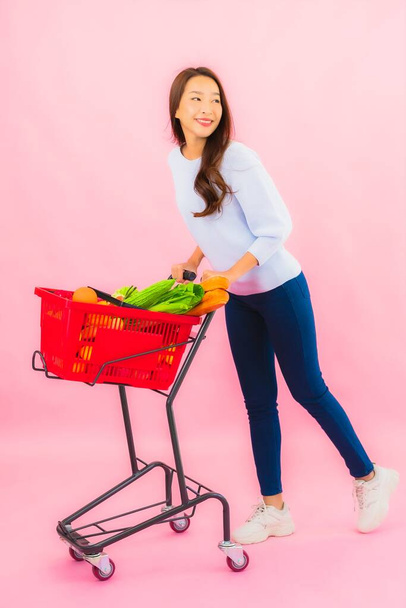 Portrait belle jeune femme asiatique avec fruits légumes et épicerie dans le panier sur fond rose isolé - Photo, image