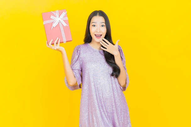 Портрет красивая молодая азиатская женщина улыбка с красной коробке подарка на цветном фоне - Фото, изображение