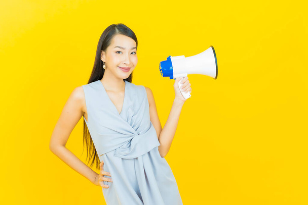 Retrato hermosa joven asiática mujer sonrisa con megáfono en color de fondo - Foto, imagen