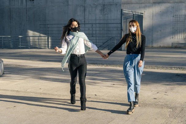 Twee mooie vrouwen vrienden lopen hand in hand terwijl ze gelukkig praten.Concept vriendschap en liefde. - Foto, afbeelding