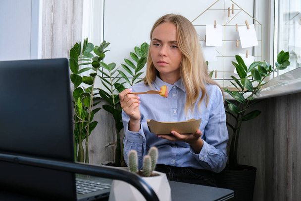 Woman holding lunch zero waste box, food delivery box with healthy meal weight loss diet menu, vegan food at workplace in office. Office employee having vegan lunch at workspace. Healthy business lunch at home - Photo, image