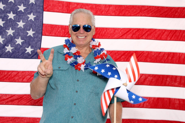Счастливый улыбающийся американец с американским флагом. Фото Бут портрет Гордого американца. Человек в фотобудке 4 июля. - Фото, изображение