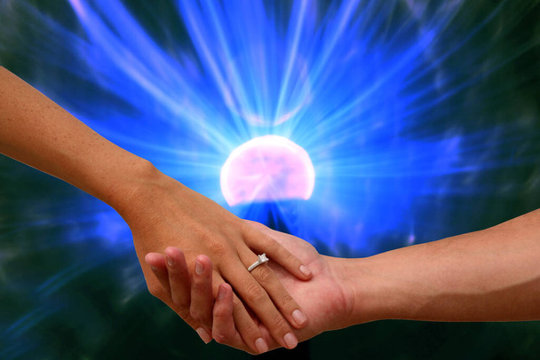 Помолвка руки с электронным плазменный шар. Пара держатся за руки с обручальным кольцом на фоне плазменного шара. - Фото, изображение