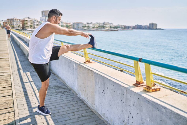 Güneşli bir günde dışarıda antreman yaptıktan sonra bacaklarını açan İspanyol bir adam. - Fotoğraf, Görsel