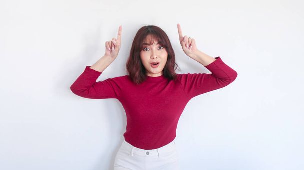 Shock Asian beautiful girl point above with red shirt in white background - Foto, imagen