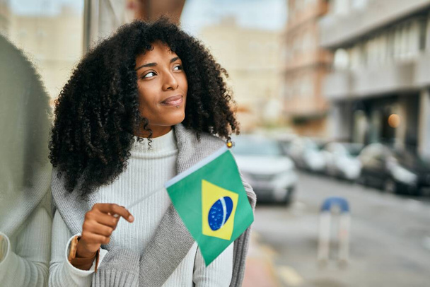 若いアフリカ系アメリカ人女性がブラジル国旗を掲揚. - 写真・画像