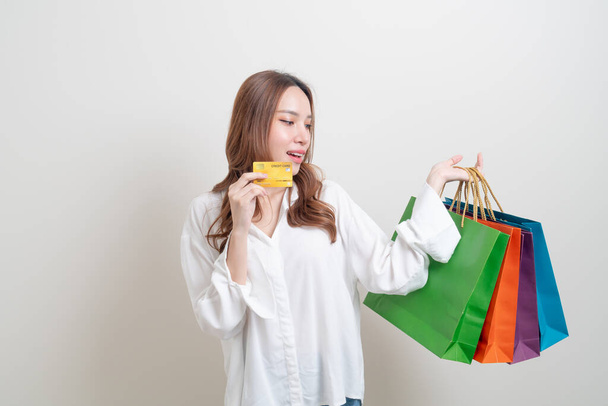 portrait beautiful Asian woman holding shopping bag and credit card on white background - Foto, Bild