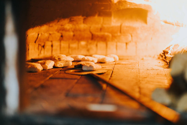 A group of undercooked pies being put into the hot wood fire - Foto, Imagem