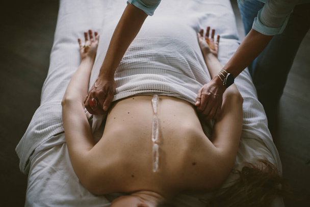 Masażystka masująca kobietę z kryształami na plecach - Zdjęcie, obraz