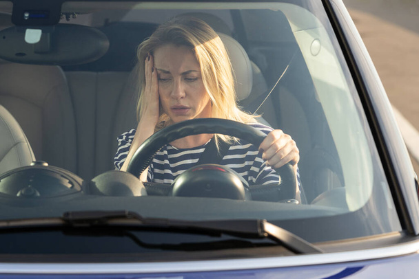 Ideges női sofőr, nézze meg a műszerfalat. Fáradt nő elromlott autóban, benzin nélkül az autópályán. - Fotó, kép