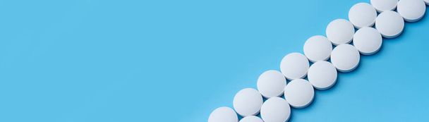 Weiße medizinische Pillen auf blauem Hintergrund in der oberen rechten Ecke. Labor für Pharmazeutika. Unter dem Text platzieren. - Foto, Bild