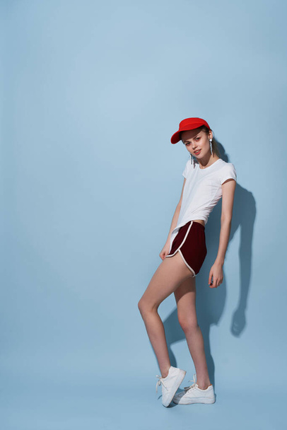 ελκυστική γυναίκα με κόκκινο καπέλο και σορτς που ποζάρουν καλοκαίρι στούντιο μόδας - Φωτογραφία, εικόνα