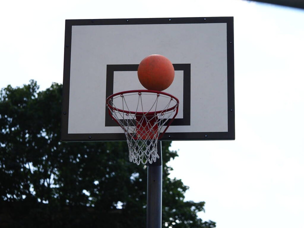 м'яч летить в баскетбольне кільце на вулиці під час гри
 - Фото, зображення