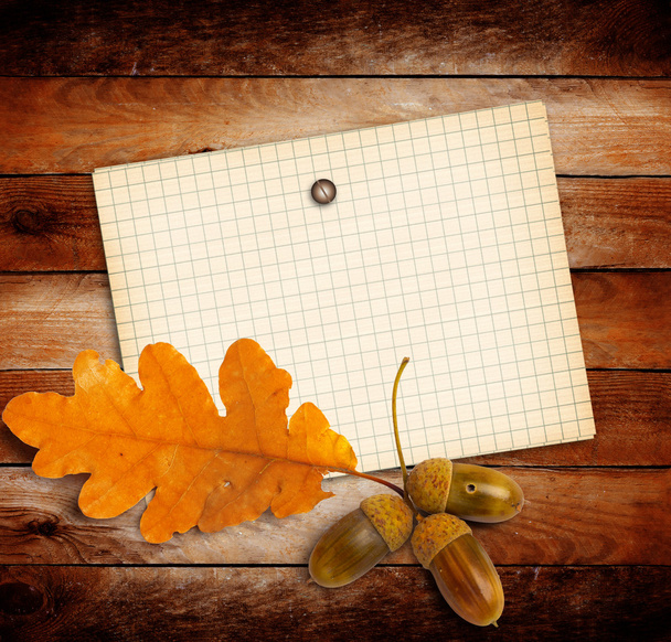 Old grunge paper with autumn oak leaves and acorns on the wooden - Foto, afbeelding