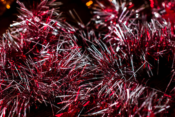 A closeup shot of red sparkly Christmas tinsel in the dark background - Фото, изображение