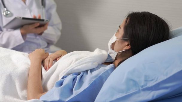 Arzt mit Mundschutz spricht kompetent mit Patient auf Krankenhausstation - Foto, Bild
