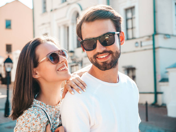 Smiling beautiful woman and her handsome boyfriend. Woman in casual summer clothes. Happy cheerful family. Female having fun. Couple posing on the street background in sunglasses.Hugging each other - Photo, image