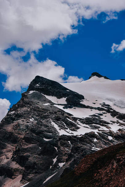 The snowy mountain tops under the cloudy dark sky in Gran Paradiso National Park in Italy - 写真・画像