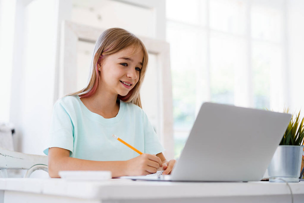 Young girl using laptop for homework at home - Fotó, kép