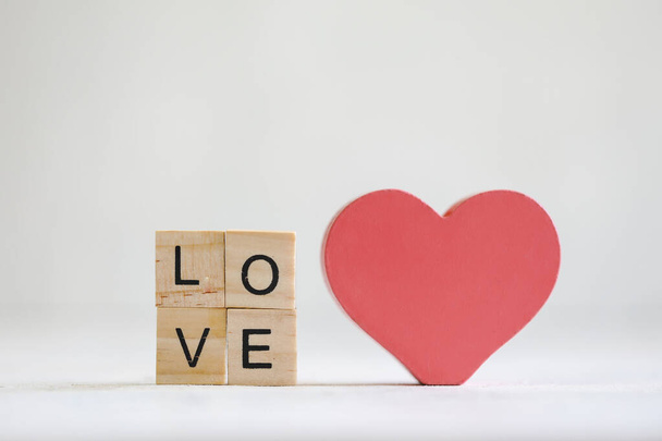 Coração de amor de madeira vermelho vibrante em exposição com pequenas letras soletrando a palavra AMOR. Fundo branco com espaço de cópia. - Foto, Imagem
