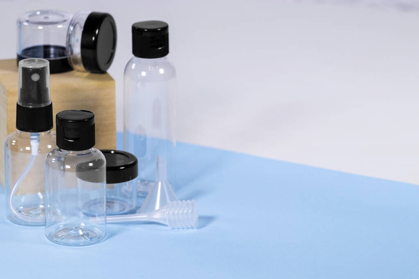 Group of Plastic clear travelling bottles for Cosmetic: soap, gel, lotion, cream, shampoo, make up and liquids on light blue Background. Modern Traveling Concept. Copy Space. Container for carryon. - Photo, image