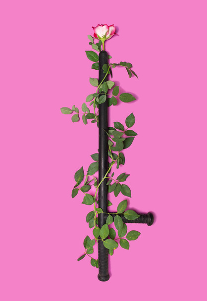 Sub rosa, confidentiality, defending minimal concept. Arrangement made of black police baton with lovely fresh rose twisted around it. Flat lay purple background. - Zdjęcie, obraz