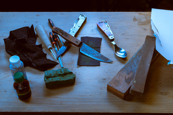Ein altes Messer schärfen. Restaurierung eines alten Messers. Schärfen Sie in der Werkstatt ein Messer. Frontansicht. - Foto, Bild