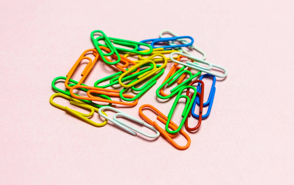Office paper clips isolated on colored background. Pink, red, blue, green, orange colorful Plastic paperclips documents staple attach tools. - Photo, Image
