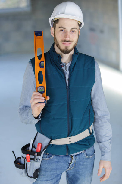 young male builder holding a spirit-level - Foto, imagen