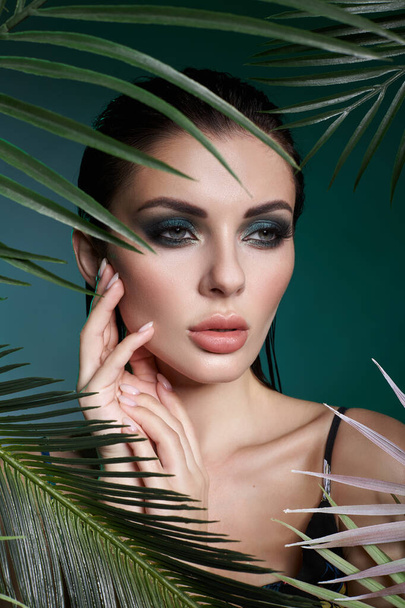 Tropical portrait sexy woman in leaves palm tree. Bright green makeup, shadow of palm leaves on girl face. Beautiful makeup - Foto, Imagem