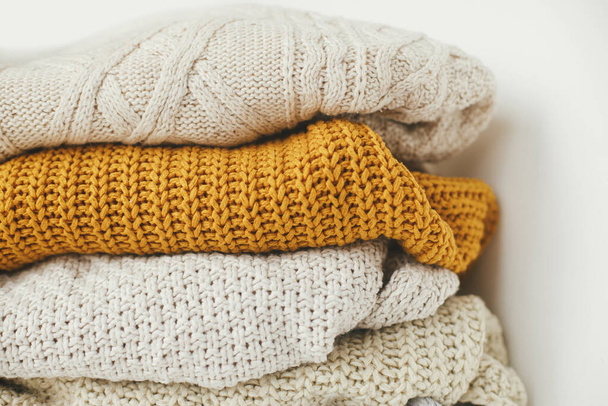Confortable fond de pull tricoté. Pile de pulls tricotés blancs, jaunes et beiges. Bonjour l'automne. Armoire élégante pour la saison froide - Photo, image