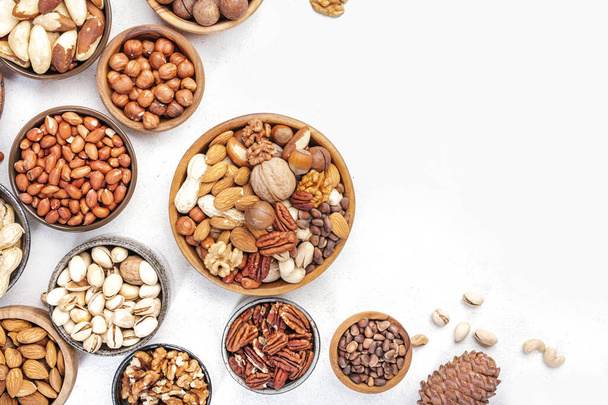 Nut mix in bowl. Almonds, hazelnuts, walnuts and other. Healthy food snack mix on white table, top view, copy space - Zdjęcie, obraz