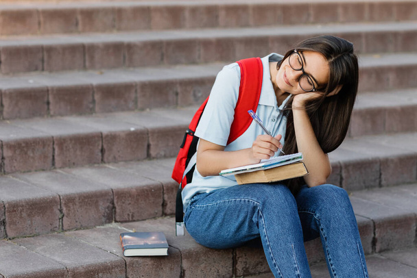 Przemyślana studentka siedzi na schodach w pobliżu uniwersytetu. - Zdjęcie, obraz