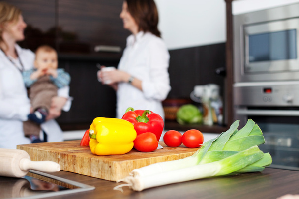 Vegetables and chopping board with women and baby - Foto, imagen
