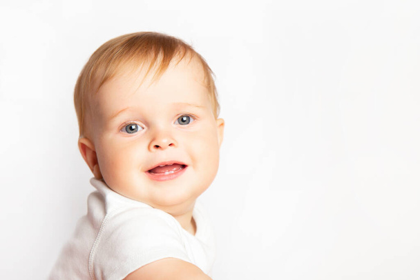 portrait of cute smiling blond caucasian baby boy in a white T-shirt on white background with copy space - Foto, Imagem