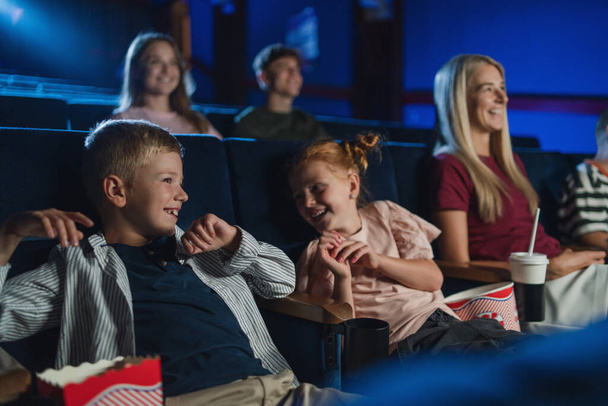 Mother with happy small children in the cinema, watching film and laughing. - Φωτογραφία, εικόνα