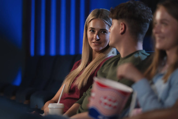 Happy young couple watching film in the cinema, talking. - Фото, зображення