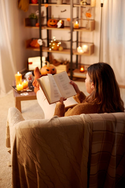 young woman reading book at home on halloween - Photo, image