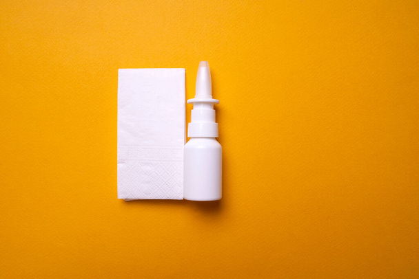 Eine Flasche Nasentropfen auf gelbem Hintergrund in Großaufnahme. Spray für die Nase. Blick von oben - Foto, Bild
