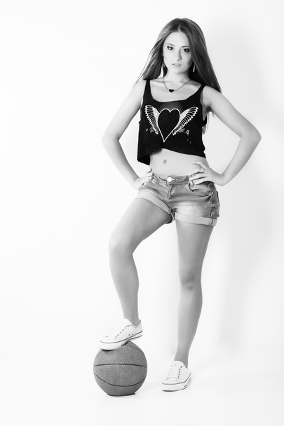 Young beautiful girl in shorts with the ball stands in the Studio on the white background - Foto, imagen