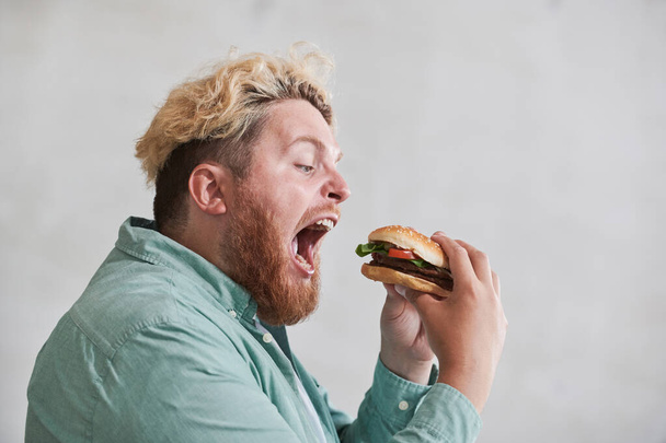 Homem com excesso de peso comer fast food - Foto, Imagem
