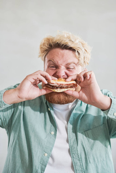 太りすぎの男がバーガーを食べる - 写真・画像