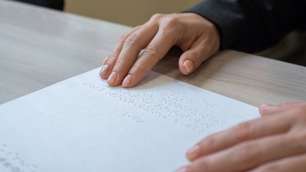 Close-up woman reads the text to the blind. Womans hands on paper with braille code. - Foto, afbeelding