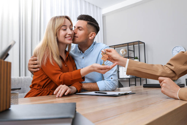 Real estate agent giving house key to couple at table in office - Foto, Imagem